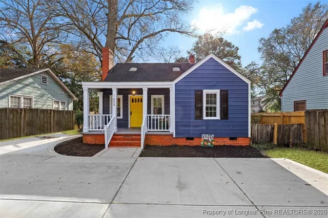 a view of a house with a yard and large tree