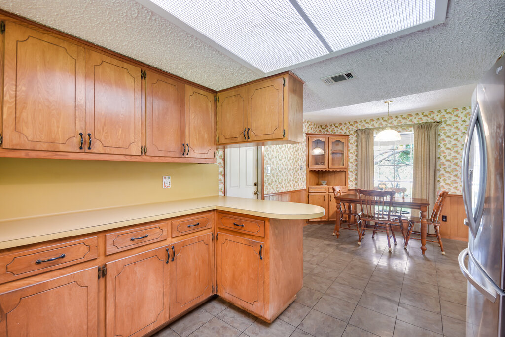301 Navajo Trail Georgetown, TX 78633 - Photo 26 of 35 Kitchen with wallpapered walls, a textured ceiling, wainscoting, and a peninsula.