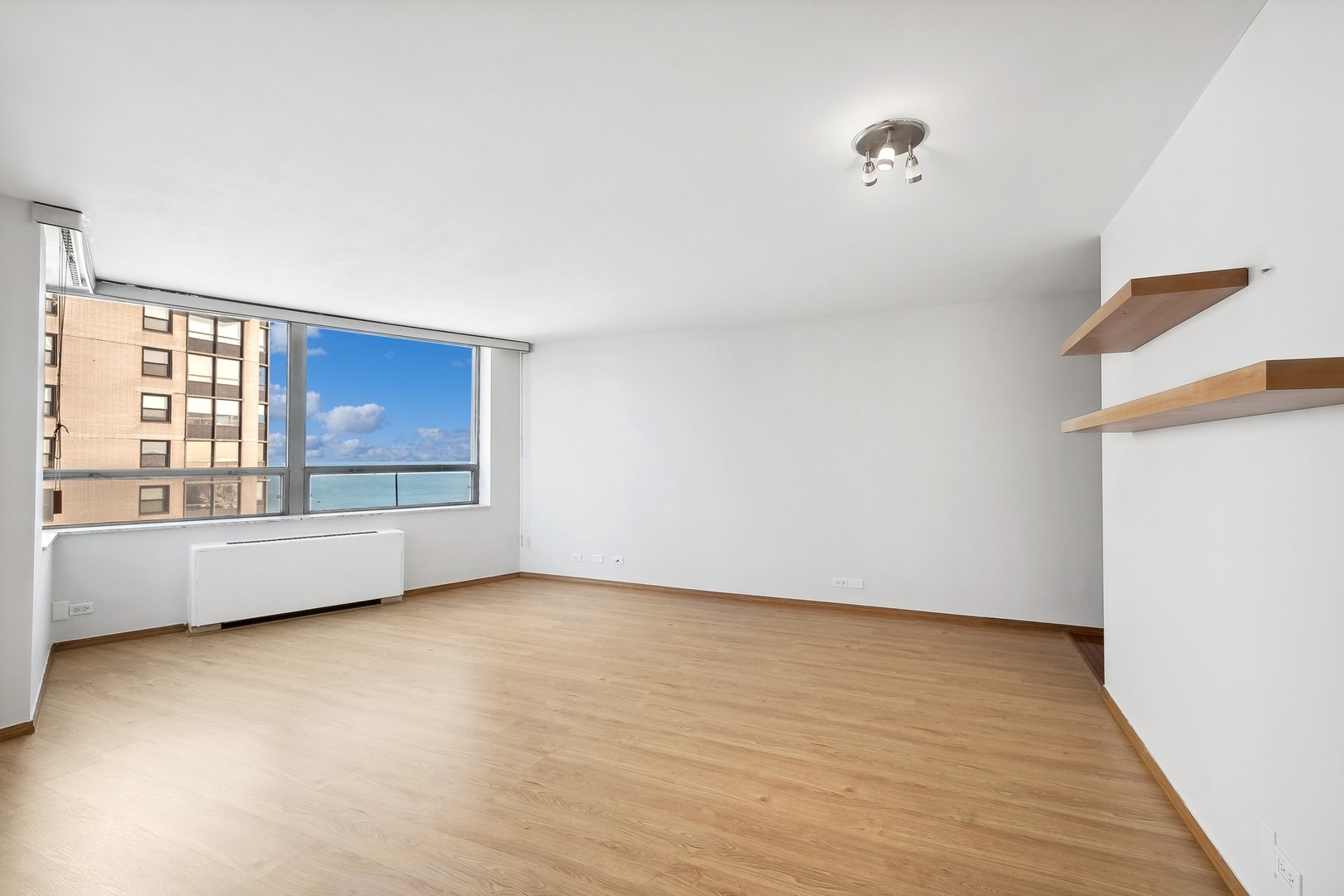 5701 North Sheridan Road, Unit 15R Chicago, IL 60660 - Photo 2 of 21 a view of an empty room with wooden floor and a window