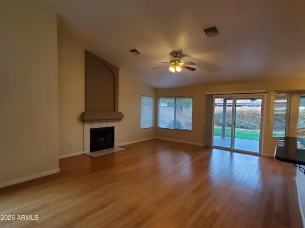 a view of empty room with wooden floor and fan