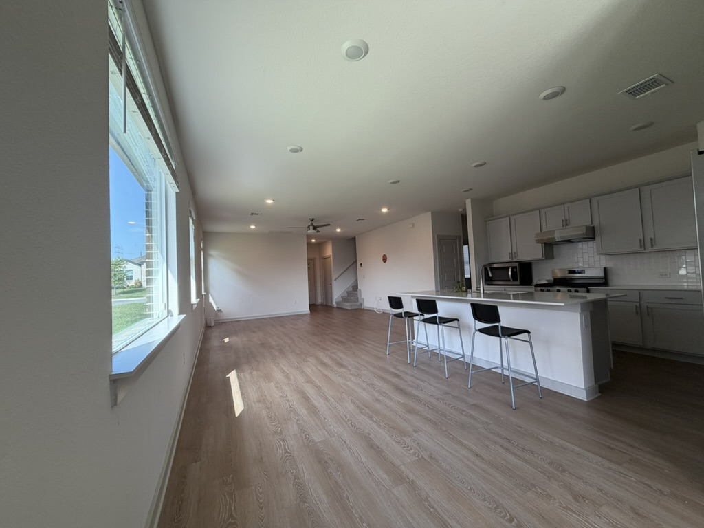 10708 Gonzales Ranger Pass Austin, TX 78754 - Photo 2 of 40 An open-concept living area boasts a modern kitchen island and warm wood flooring throughout.