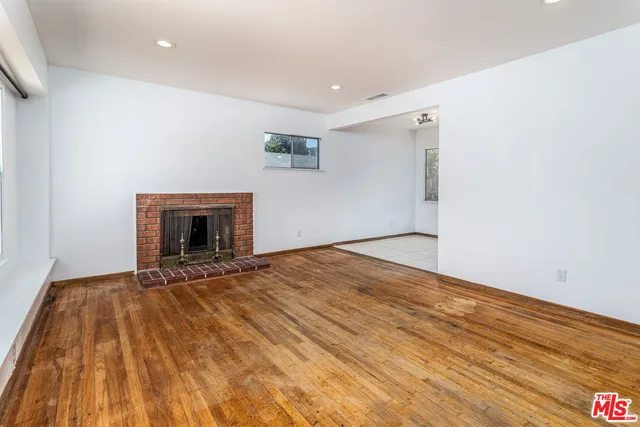 a view of empty room with wooden floor and fireplace