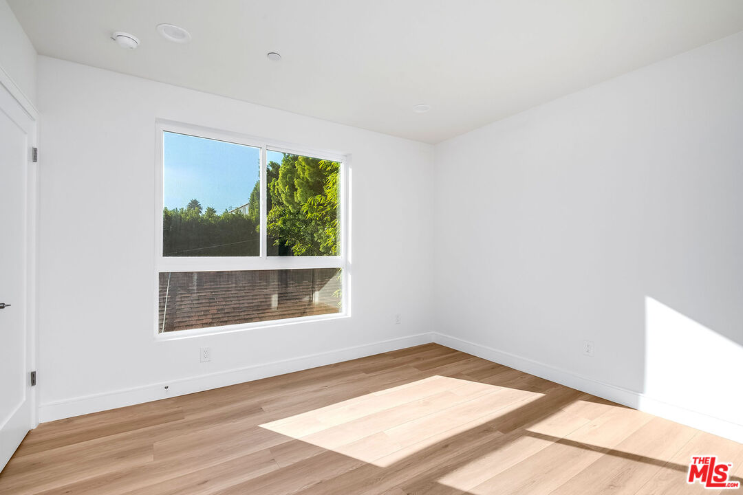 10803 Kling Street Toluca Lake, CA 91602 - Photo 19 of 25 a view of an empty room with wooden floor and a window