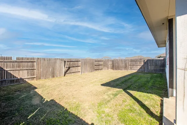 a view of a house with backyard and wooden fence