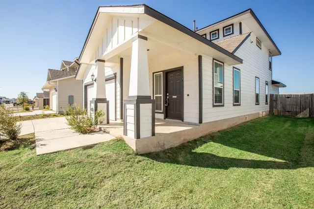 a view of a white house with a big yard and potted plants
