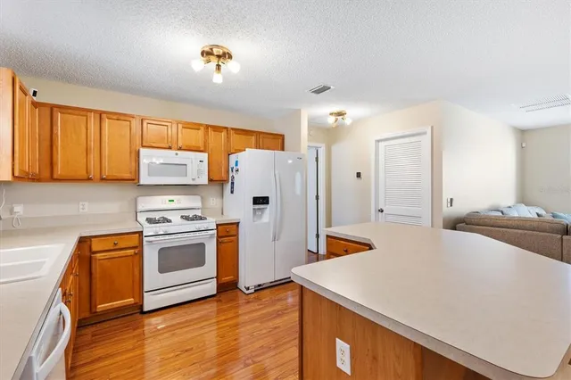 a kitchen with stainless steel appliances a stove a refrigerator a sink a stove and white cabinets with wooden floor