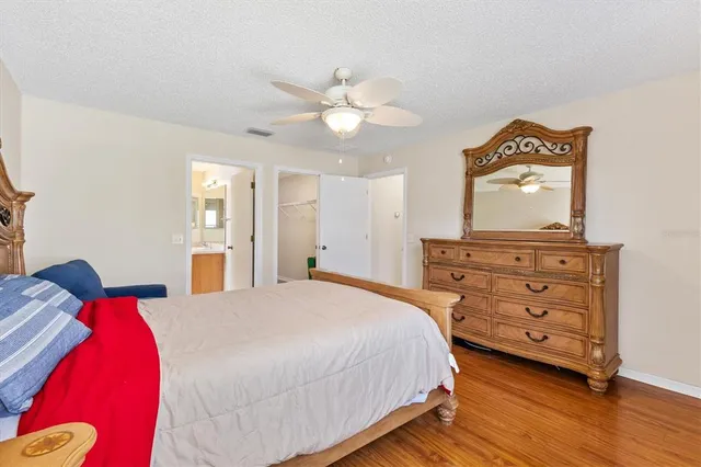 a bedroom with a bed and a dresser with wooden floor