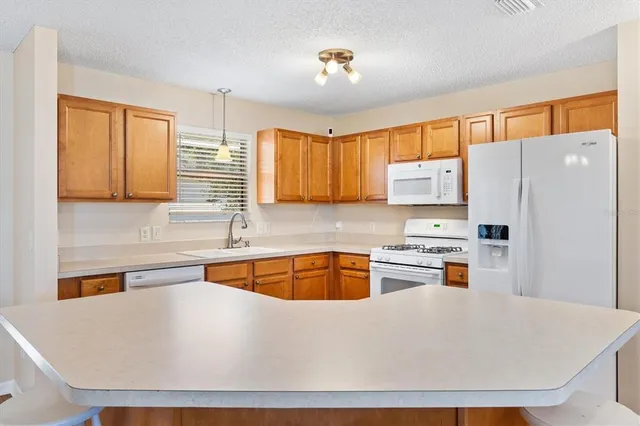 a kitchen with stainless steel appliances a refrigerator a sink a stove a microwave and wooden cabinets