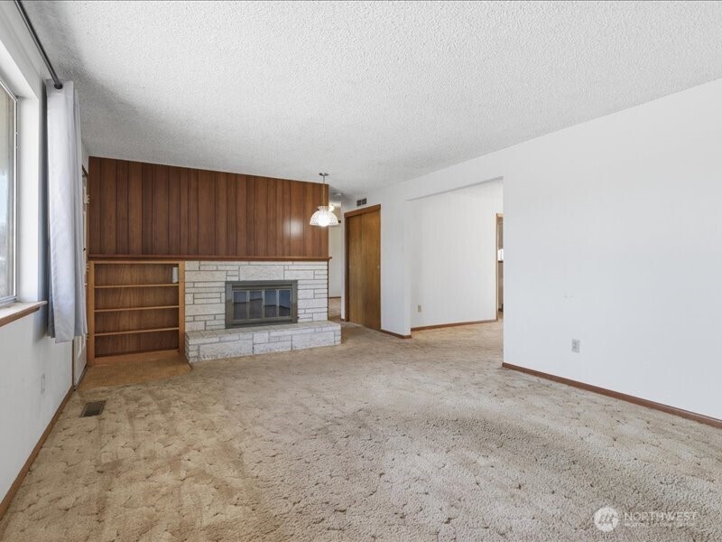 702 West Ridge Drive Omak, WA 98841 - Photo 5 of 26 an empty room with a fireplace and cabinet