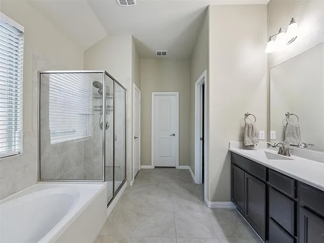 a bathroom with a tub sink shower and two mirror