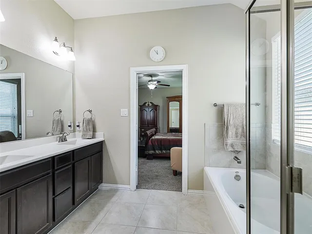 a en suite bathroom with a double vanity sink a mirror and a bathtub