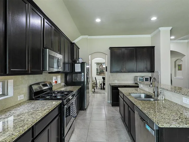 a kitchen with stainless steel appliances granite countertop a sink stove and refrigerator
