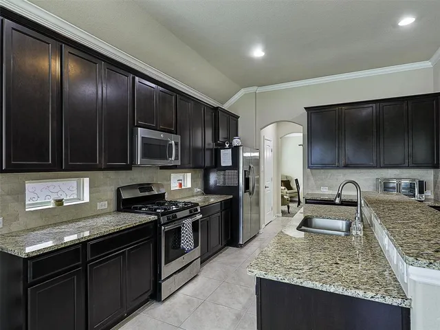 a kitchen with stainless steel appliances granite countertop a sink stove and refrigerator