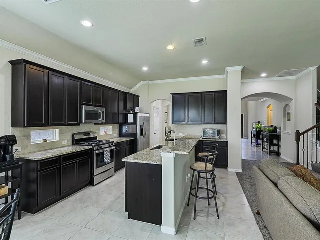 a kitchen with stainless steel appliances kitchen island granite countertop a stove top oven a sink a counter top space and cabinets