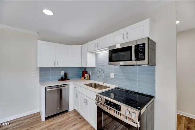 a kitchen with stainless steel appliances granite countertop a stove and white cabinets