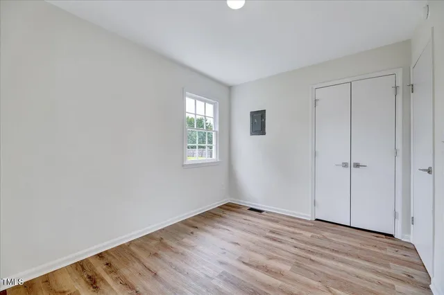 a view of empty room with wooden floor and fan