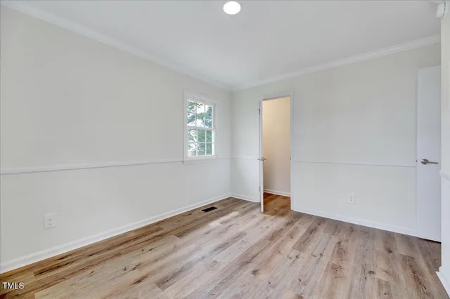 an empty room with wooden floor closet and windows