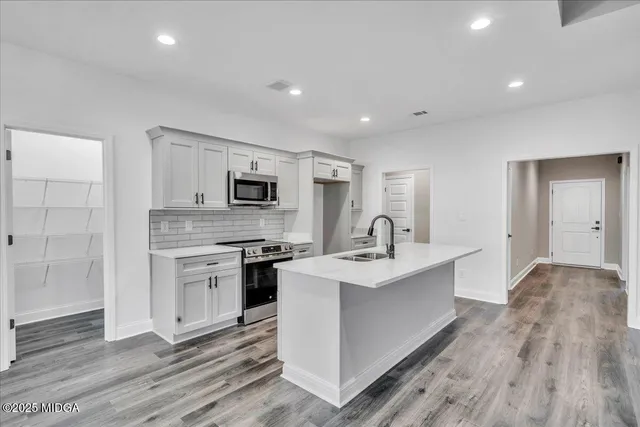 a view of a kitchen with sink stainless steel appliances and wooden floor
