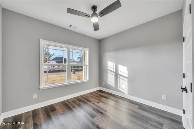 a view of an empty room with a window and wooden floor