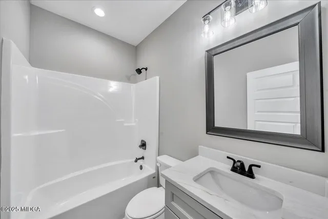 a bathroom with a bathtub shower sink vanity mirror and toilet
