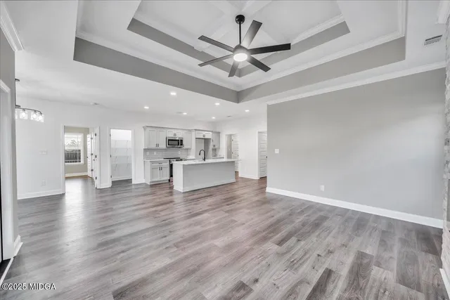 a view of a livingroom with a ceiling fan wooden floor and a ceiling fan
