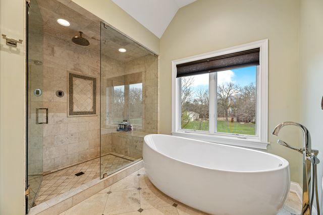 a bathroom with a large tub a shower and view