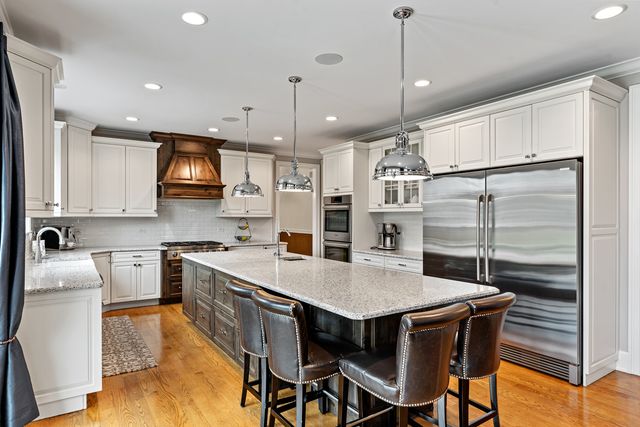 a kitchen with stainless steel appliances granite countertop a kitchen island a stove a table and chairs in it
