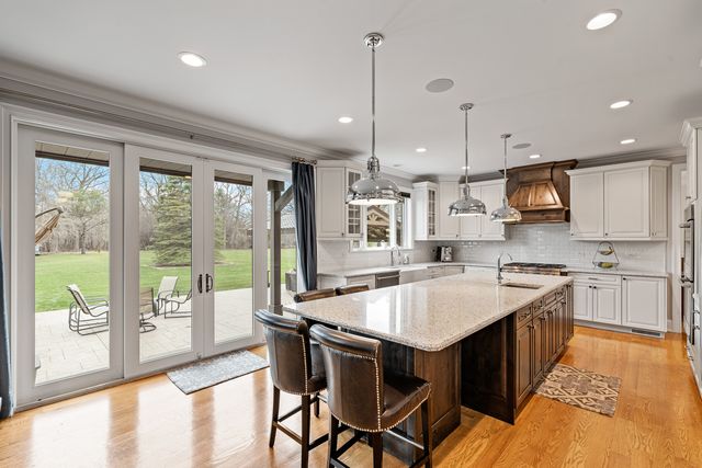 a kitchen with stainless steel appliances granite countertop a stove top oven a sink dishwasher a dining table and chairs with wooden floor