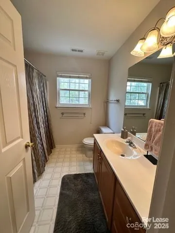 a bathroom with a sink a toilet a mirror and a window