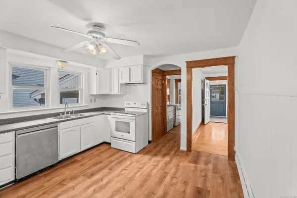 a view of a kitchen with a sink and dishwasher a refrigerator with wooden floor
