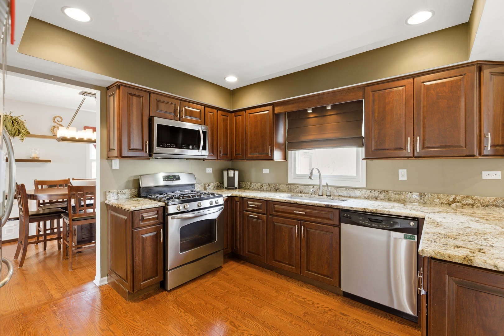 6900 Olde Gatehouse Road Tinley Park, IL 60477 - Photo 14 of 37 a kitchen with stainless steel appliances granite countertop a stove top oven a sink dishwasher a dining table and chairs with wooden floor