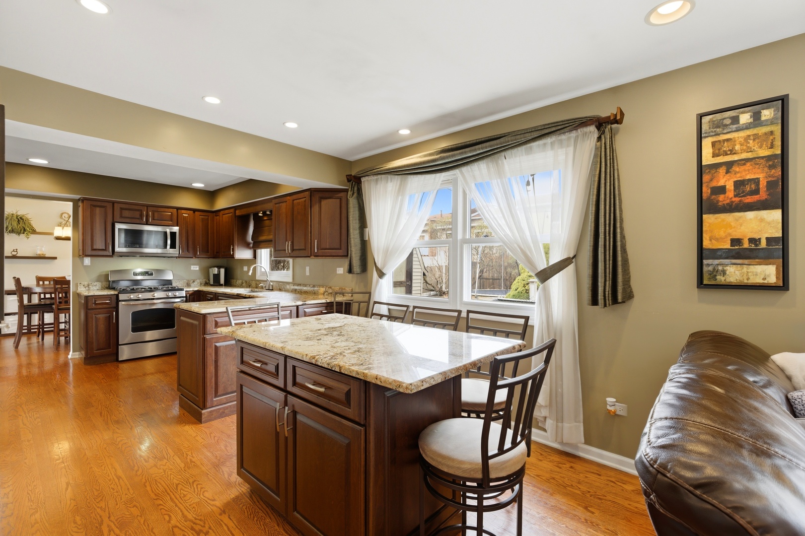 6900 Olde Gatehouse Road Tinley Park, IL 60477 - Photo 15 of 37 a kitchen with stainless steel appliances granite countertop a stove top oven a sink a dining table and chairs with wooden floor