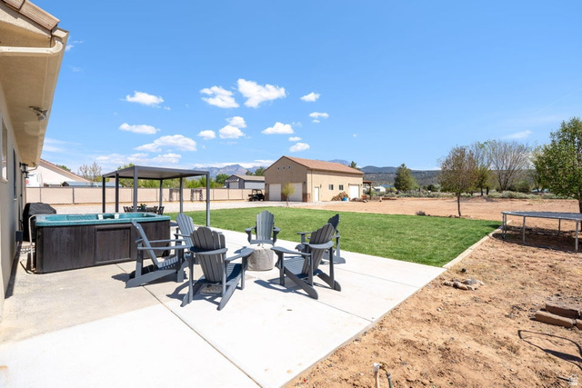 7776 Wagon Road East St. George, UT 84770 - Photo 52 of 76 Fenced backyard with a trampoline, a patio area, a fire pit, a mountain view, and an outbuilding