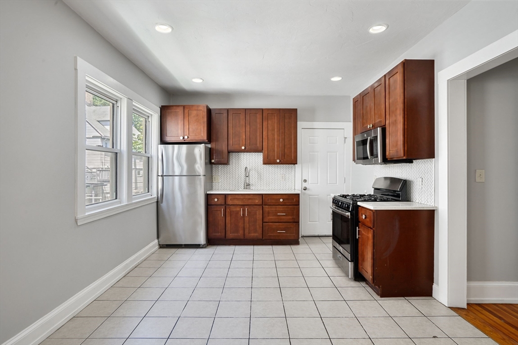 32 Millet Street, Unit 2 Boston, MA 02124 - Photo 2 of 14 a kitchen with stainless steel appliances granite countertop a stove a sink and a refrigerator