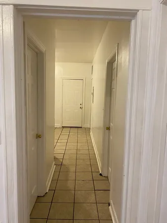 a view of a hallway with wooden floor and a bathroom