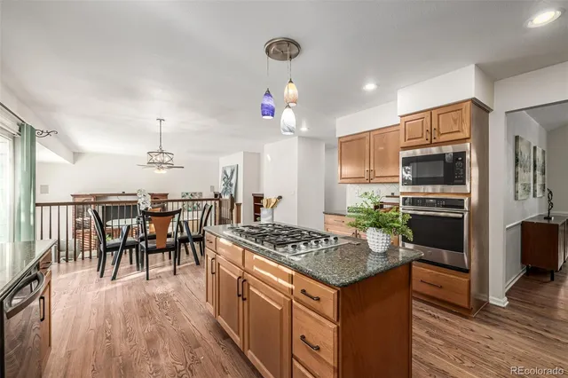 a kitchen with stainless steel appliances granite countertop a stove refrigerator and a dining table with wooden floor