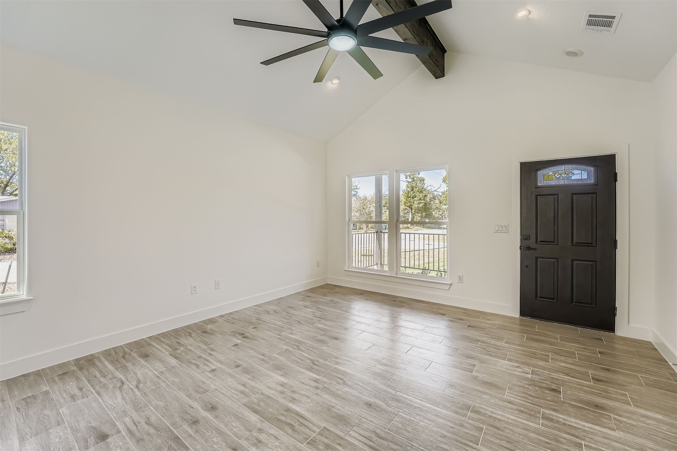 701 East 3rd Street Elgin, TX 78621 - Photo 6 of 35 Bright living room with large windows, vaulted ceiling, and ceiling fan