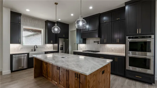 a kitchen with stainless steel appliances granite countertop a sink a refrigerator and a stove