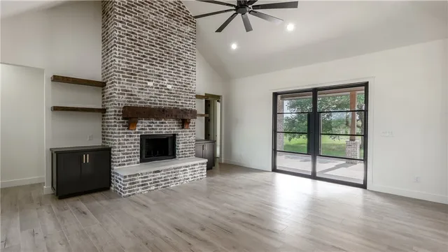 an empty room with wooden floor fireplace and windows
