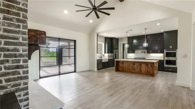 a large kitchen with stainless steel appliances a large counter top a stove and a refrigerator