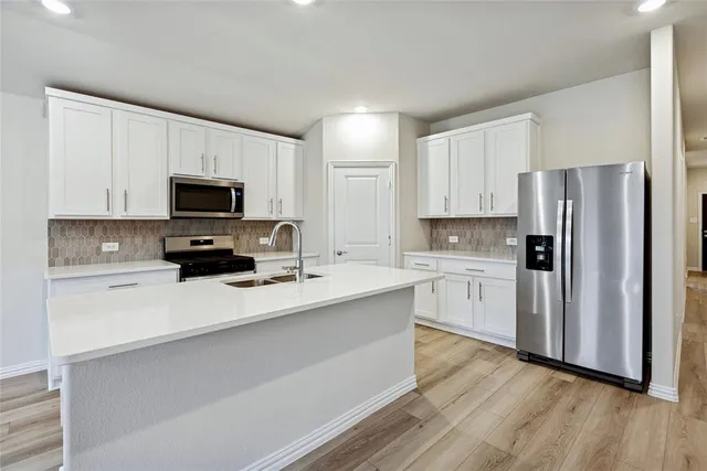 a kitchen with white cabinets and stainless steel appliances
