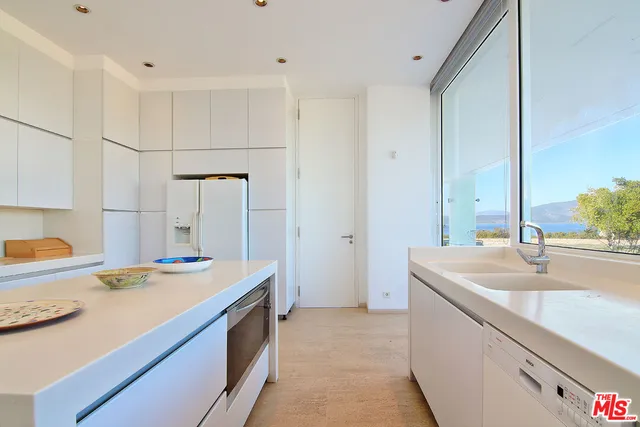 a bedroom with a large bed and a flat tv screen on dresser next to a window