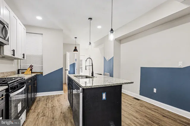 a kitchen with granite countertop a sink stove and wooden floor