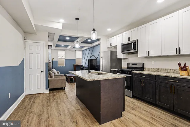 a kitchen with kitchen island granite countertop a sink appliances and cabinets