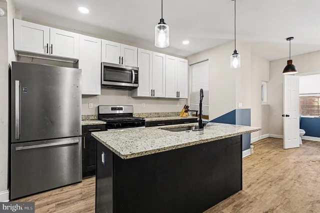 a kitchen with kitchen island granite countertop a sink refrigerator and microwave