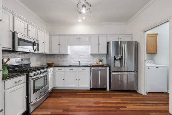 a kitchen with granite countertop a refrigerator stove top oven and cabinets