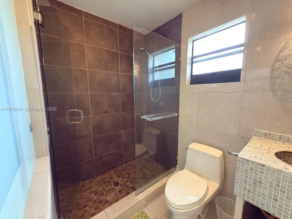 a white toilet sitting next to a bathroom sink and a shower