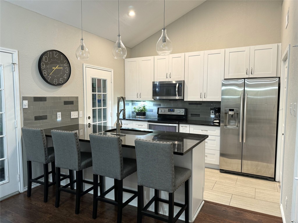 a kitchen with stainless steel appliances a table chairs refrigerator and microwave