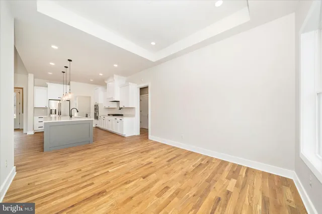 a view of a hallway with wooden floor and a bathroom