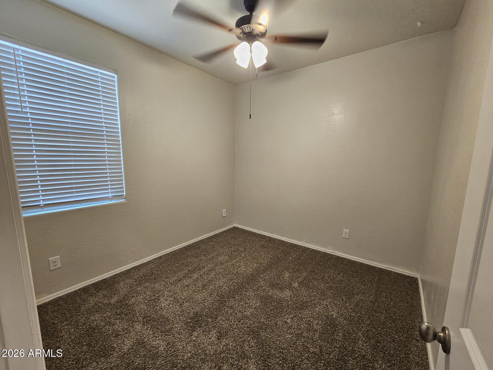25573 West Coles Road Buckeye, AZ 85326 - Photo 10 of 12 en empty room with ceiling fan and window